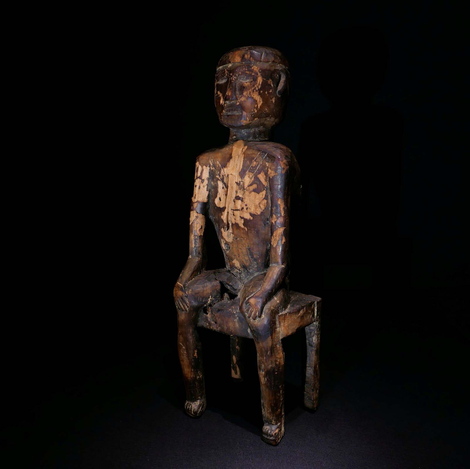 Würdenträger auf einem Stuhl. Gesichts-und Körper-Tautuirungen. Holz, aus einem Stück geschnitzt. Mitte 20.Jhdt. Naga / Nordostindien. H 68 cm, 2500.- €